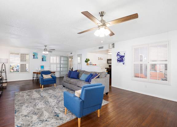 A living room with a blue sofa and a ceiling fan.