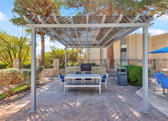 A patio with a table and chairs under a pergola.
