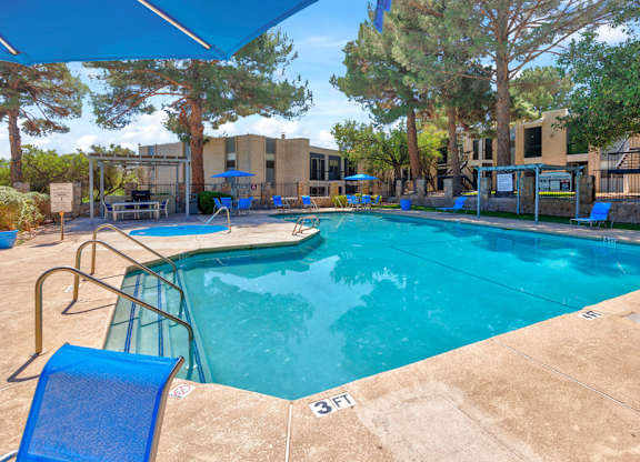 A swimming pool surrounded by trees and a building in the background.