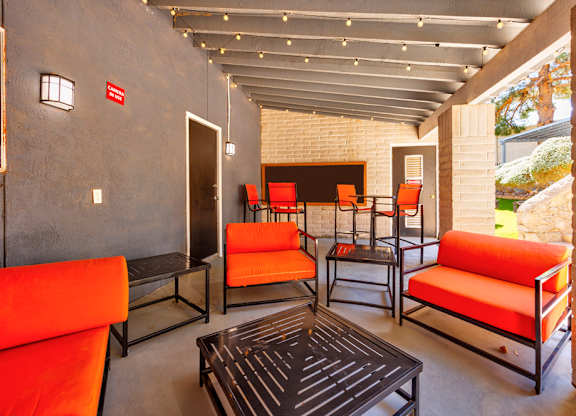 A patio with orange couches and a black coffee table.