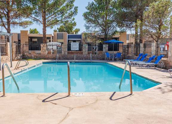 A pool surrounded by trees and a fence.
