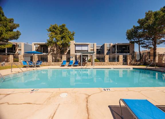 A swimming pool with a blue lounge chair and a building in the background.