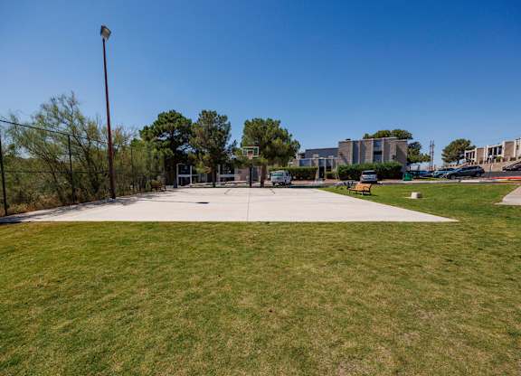 A park with a fence and a building in the background.