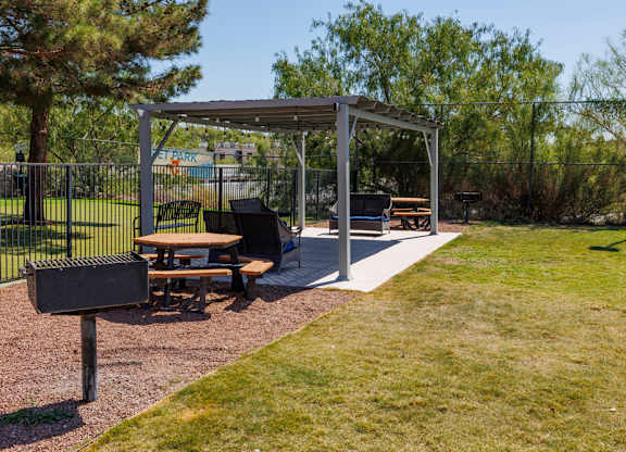 A picnic area with a grill and picnic tables.