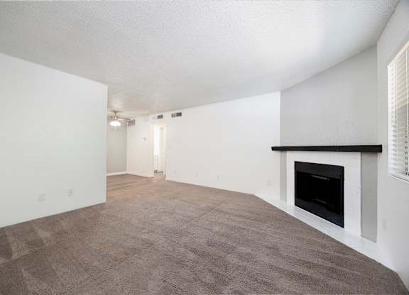 A large, empty room with a fireplace on the right side.