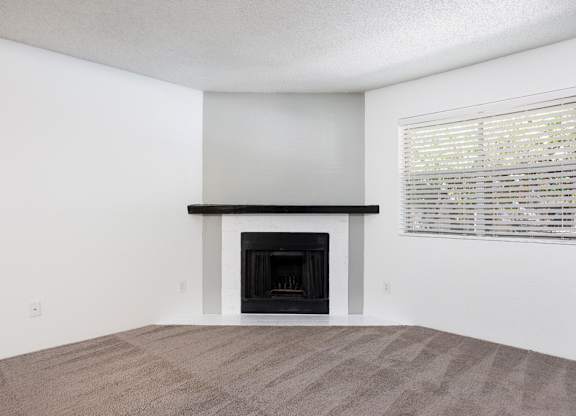 A room with a fireplace and a window with blinds.