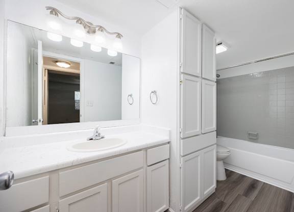 A white bathroom with a sink, mirror, and bathtub.