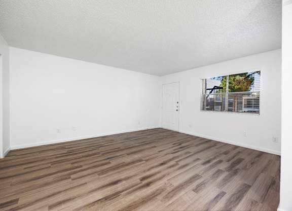 A room with wooden flooring and white walls.
