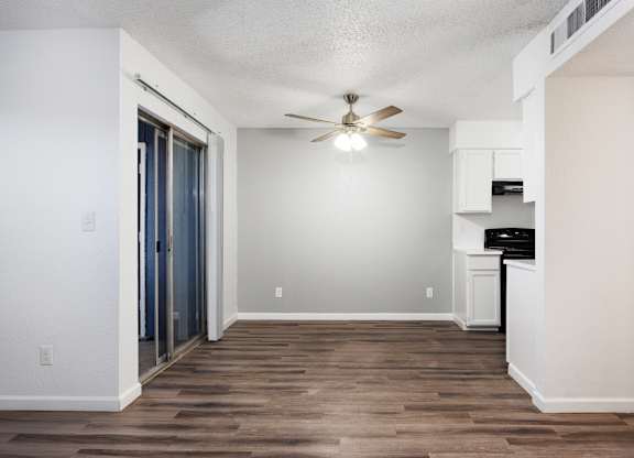 A room with a ceiling fan and a wooden floor.