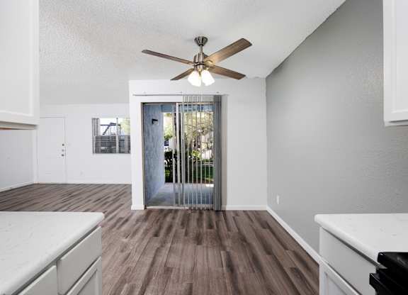 A room with a ceiling fan and wooden flooring.