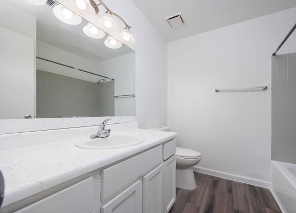 A white bathroom with a sink, toilet, and a mirror.