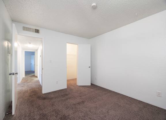 A room with white walls and carpeted floor with two doors.