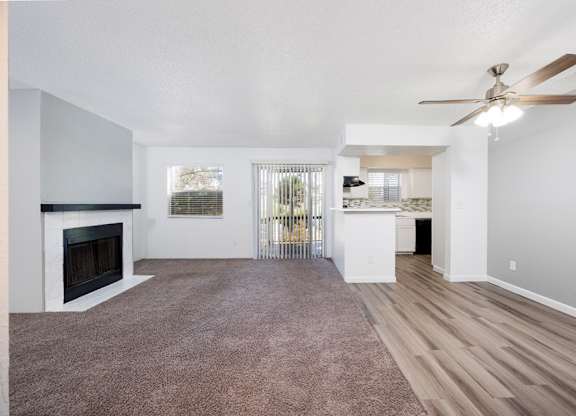 A spacious living room with a fireplace and a ceiling fan.