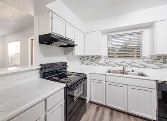 A kitchen with white cabinets and a black stove top oven.