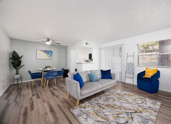 A living room with a grey couch, blue chairs, and a wooden floor.