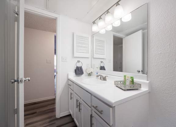 A bathroom with a white counter and a mirror above it.