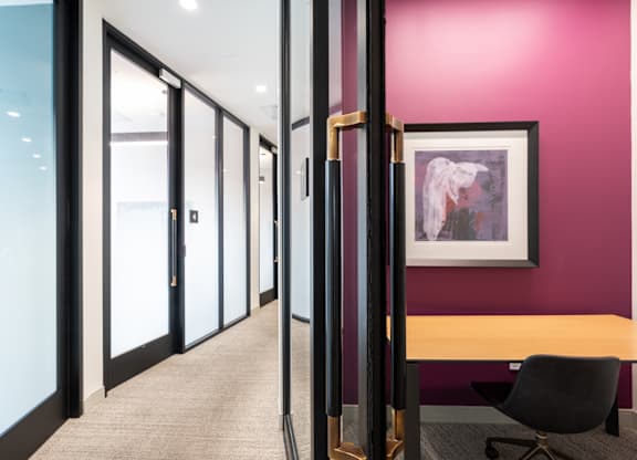 A hallway with a black chair and a framed picture on the wall.