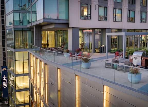 A modern building with a glass balcony and outdoor furniture.