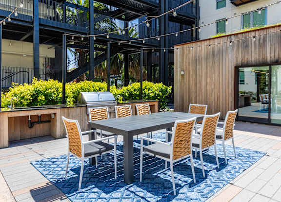 A table surrounded by chairs is on a patio.