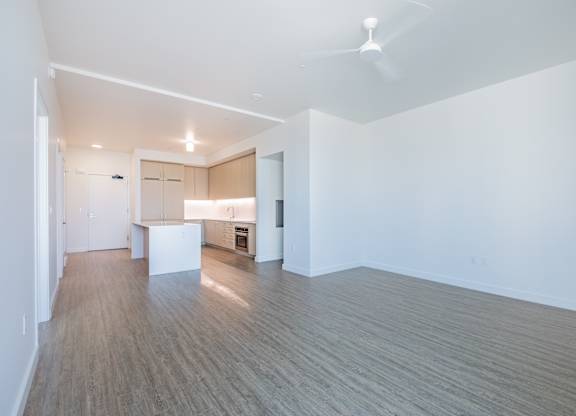 A room with a kitchen area and a dining table.
