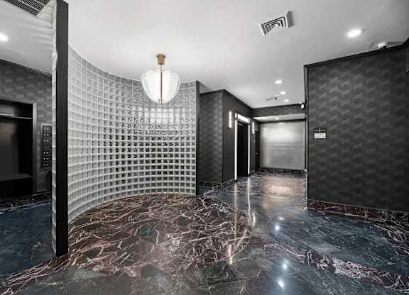 A hallway with a marble floor and a wall covered in a grid-like pattern.