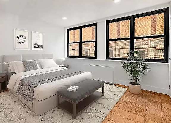 A bedroom with a large bed and a potted plant.