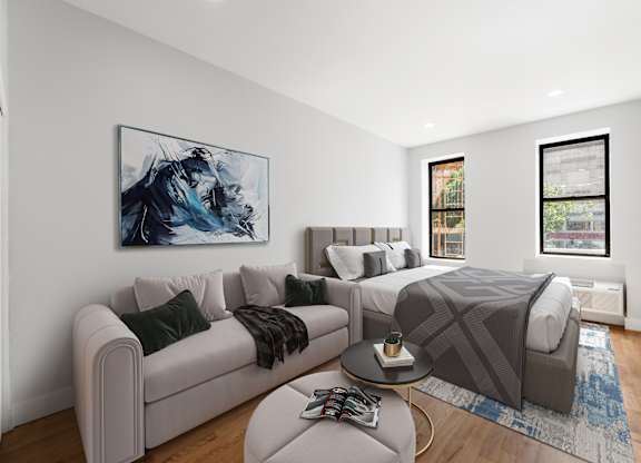 A modern living room with a grey couch, a coffee table, and a large painting on the wall.
