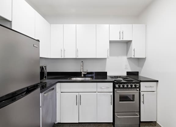 A modern kitchen with white cabinets and stainless steel appliances.
