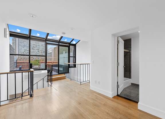 A room with a white wall and a door leading to a balcony.