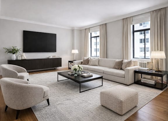 A modern living room with a grey sofa, a white armchair, a coffee table, and a flat-screen TV mounted on the wall.