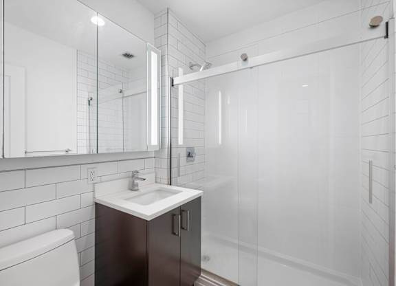 A white bathroom with a toilet, sink, and mirror.
