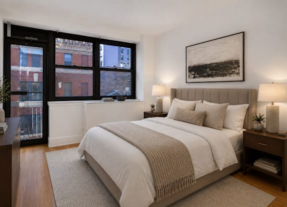 A bedroom with a large bed and a window overlooking a city.