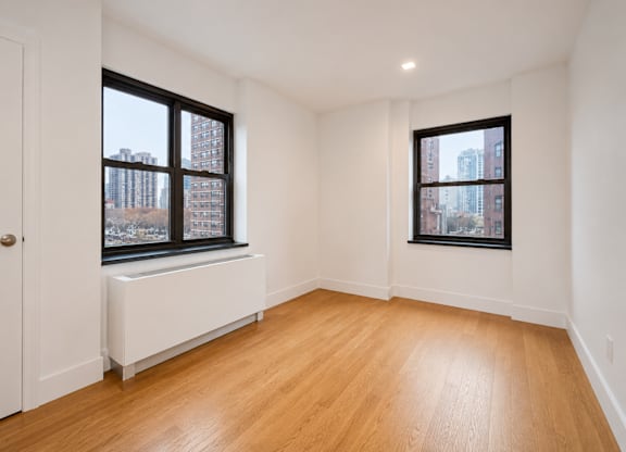 A room with wooden floors and two windows.