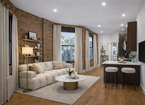 A modern living room with a white sofa, a coffee table, and a flat-screen TV mounted on the wall.