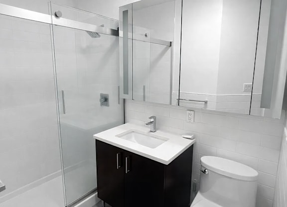 A white bathroom with a sink, toilet and shower.