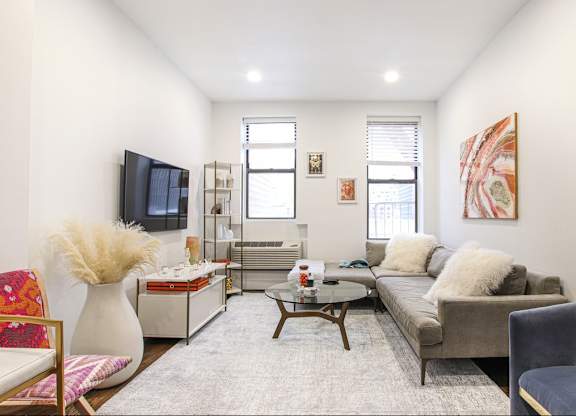 A living room with a grey couch, a white vase, a red chair, and a painting on the wall.
