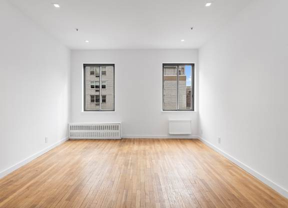 A room with wooden floors and two windows.