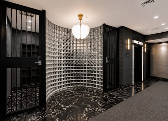 A hallway with a black and white checkered wall and a light hanging from the ceiling.