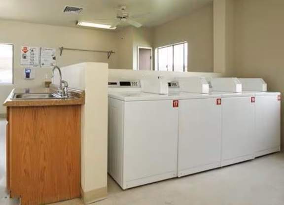 A clean, empty room with a sink and a row of white cabinets.