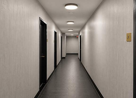A long hallway with doors on both sides and a sign on the wall.