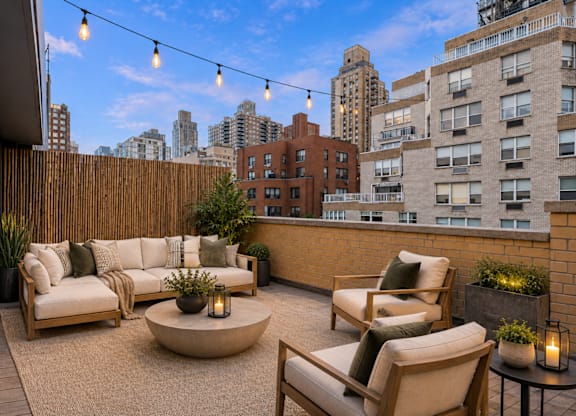 A patio with a couch, chairs, and a table with a lit candle on it.