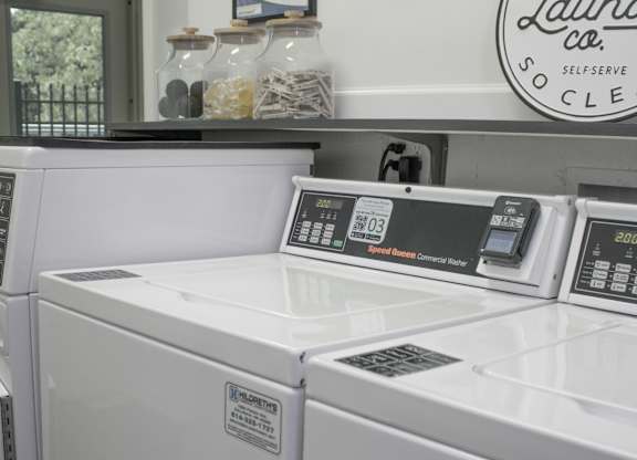 A washing machine in a laundromat with a sign that says "Go Off The Laundry Co.".