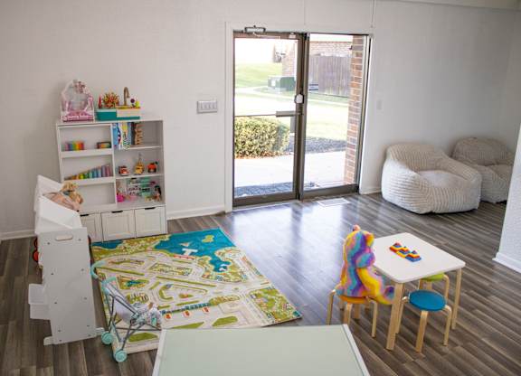 A room with a white bookshelf and a play mat on the floor.