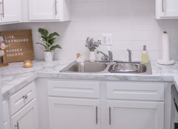 a white kitchen with white cabinets and a sink
