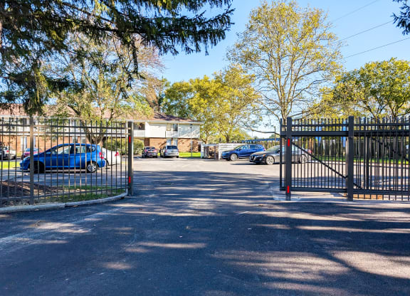 a gate to a parking lot with cars behind it
