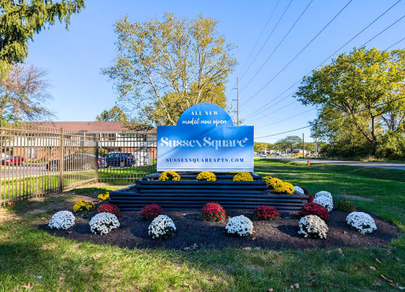 the sign is in the middle of a park with flowers