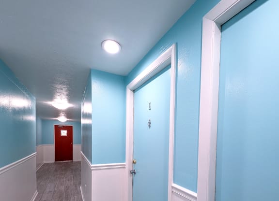 an empty hallway with blue walls and a red door