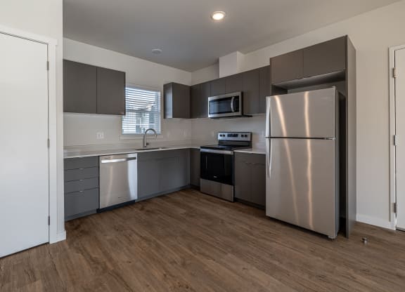 an empty kitchen with stainless steel appliances and gray cabinets at Sagecrest Apartments, Wenatchee, WA, 98801