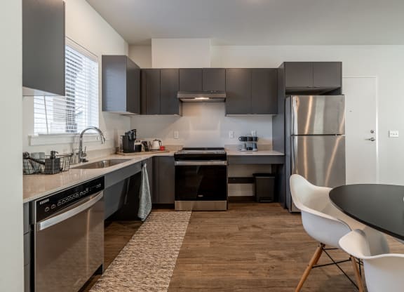 an open kitchen with stainless steel appliances and a dining room table at Sagecrest Apartments, Wenatchee, WA, 98801