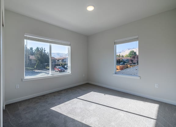 an empty living room with two windows and a rug at Sagecrest Apartments, Wenatchee